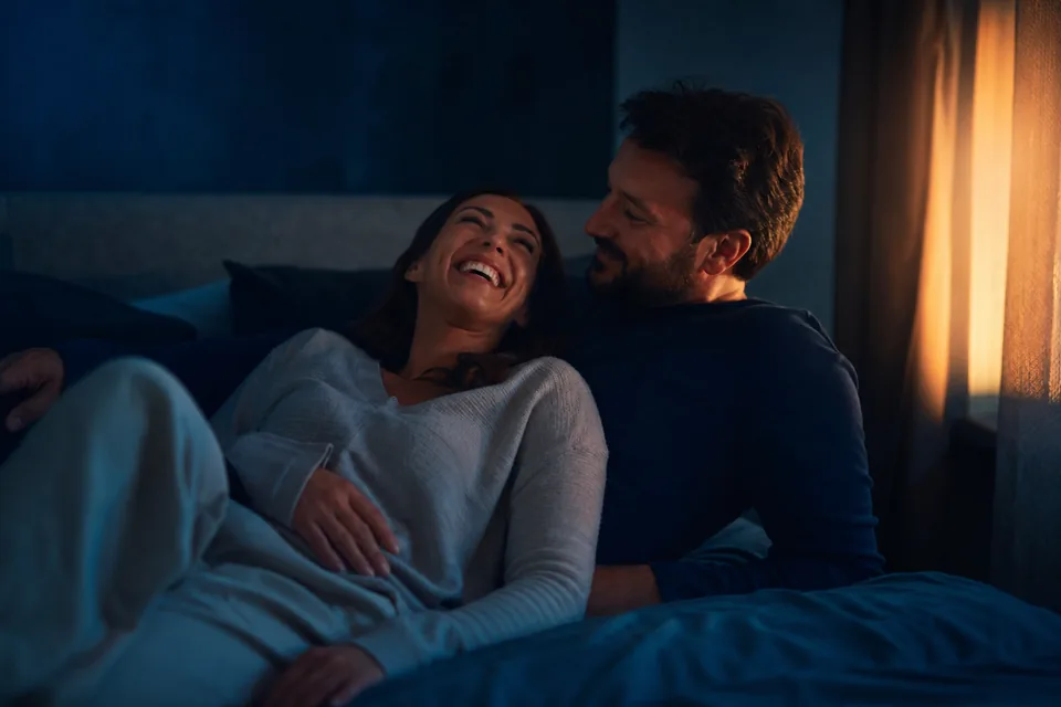 Couple lying close and laughing on a bed